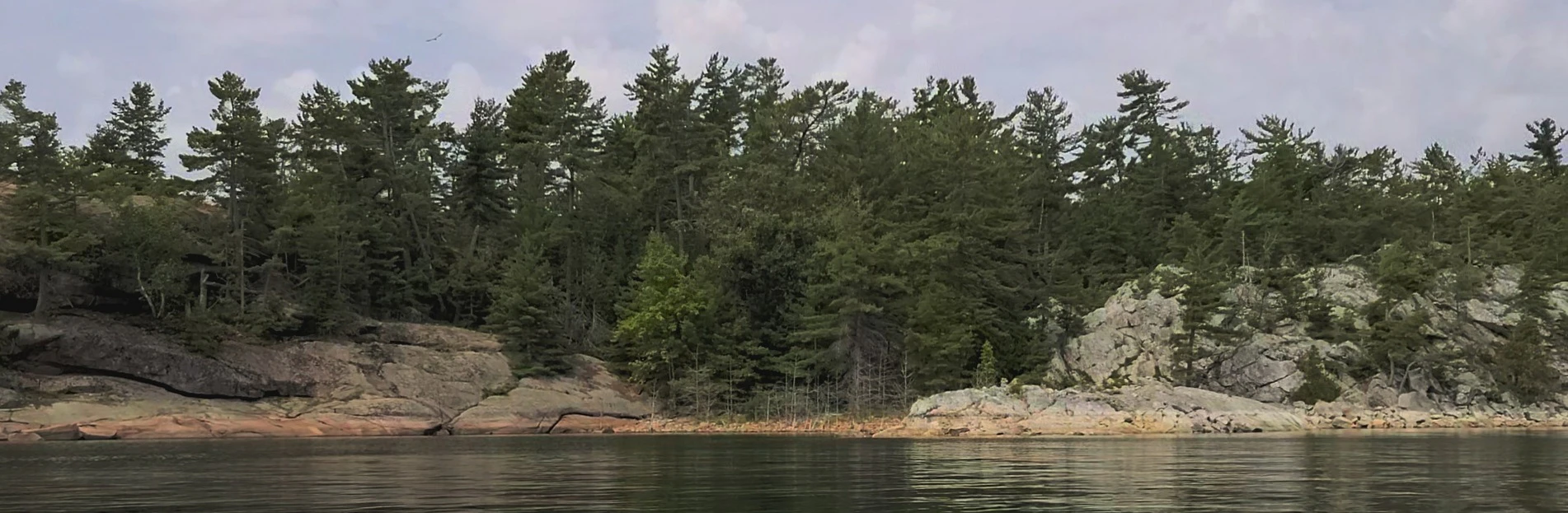 Western Shoreline of the Benjamind islands with red granite rock, white quartzite,
                trees and clear water